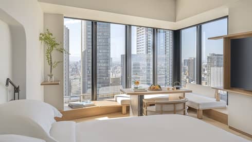 Luxurious guest room at Four Seasons Hotel Osaka with skyline views, modern decor, and serene seating area.