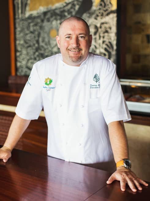 Portrait photo of Executive Chef Thomas Bellec in uniform, standing at table