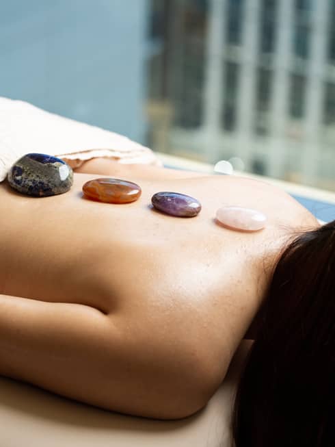 Woman laying on massage table with stones lined on her back.