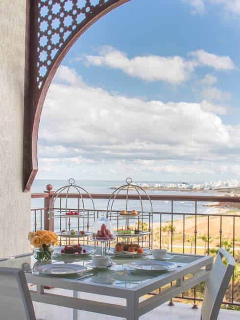 Balcony table with Afternoon Tea service, trays with pastries, sweets