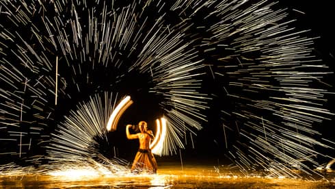 Streaks of light around man spinning fire 