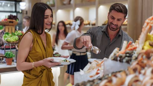 Two guests serve themselves from a seafood buffet