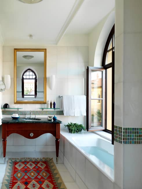 Small tub under open window in bright bathroom with sink