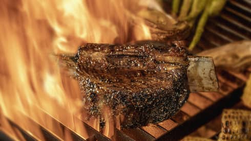 Close-up of chargrilled steak, asparagus and corn on grill grates