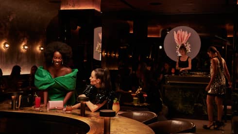 Two women in dresses at a bar.