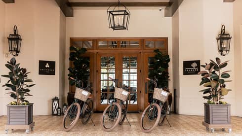 Three vintage bicycles with wicker baskets are lined up in front of the inviting entryway of Four Seasons’s Driftwood spa.