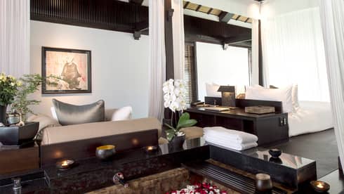 Pool Villa candle-lit tub filled with flower petals in middle of bright room, sofas