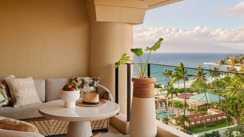 Covered, furnished lanai of a resort room overlooking resort grounds and beach