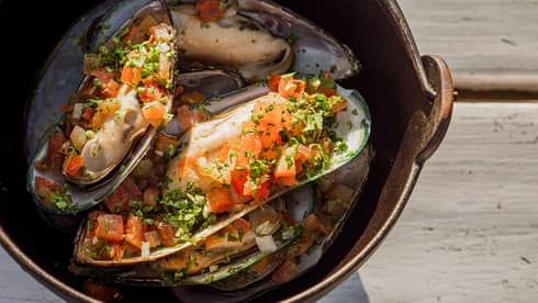 In-shell mussels with tomato relish and herbs in cast iron pot
