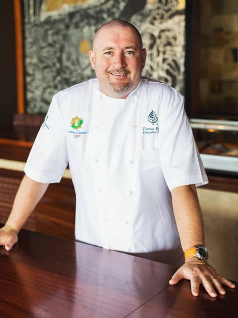 Portrait photo of Executive Chef Thomas Bellec in uniform, standing at table