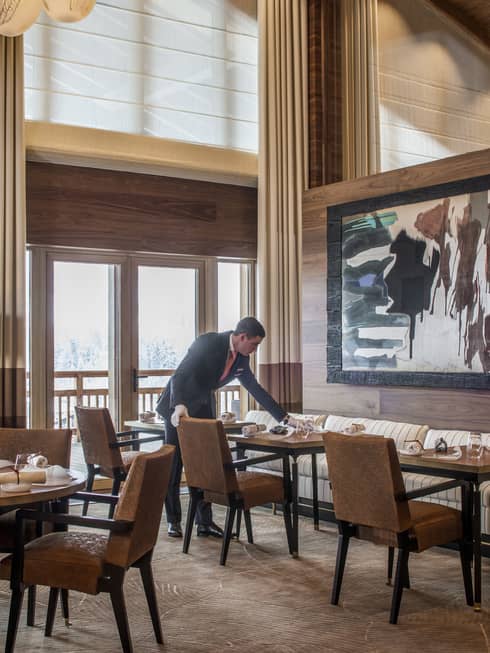 Server sets dining table under large, framed abstract painting in Le 1920 restaurant