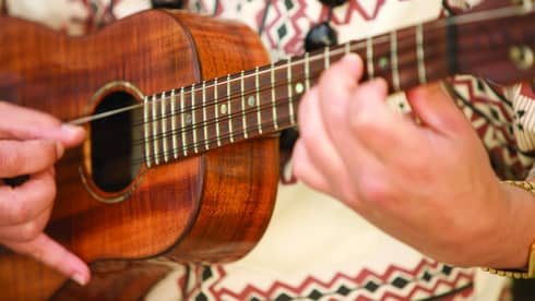 Close up of person playing ukulele instrument
