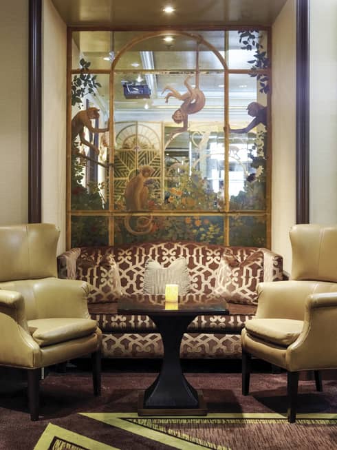 Windows Lounge brown silk patterned sofa, yellow armchairs under mural, glowing candle on table