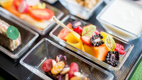 Close-up of small glass dishes with fresh melon, berries, small wood spoon