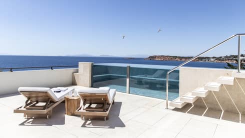 Raised, glass-enclosed pool on a private terrace with two chaise lounges