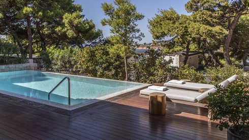Wooden deck with two lounge chairs, pool, trees
