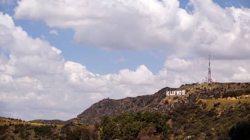 Hollywood sign on green Los Angeles hills against blue sky