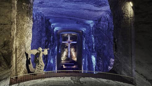 Zipaquirá salt mine cathedral hallway with angel statue and cross in dark tunnel illuminated blue