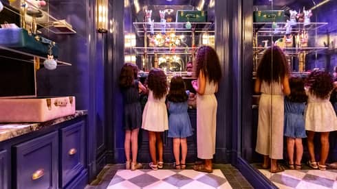 A  mother and three young daughters looking at shelves in a closet.