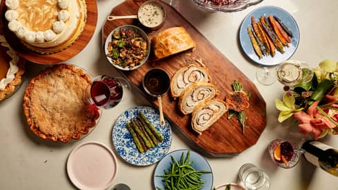 An assortment of Thanksgiving food, including pie, vegetables, bread and ham.