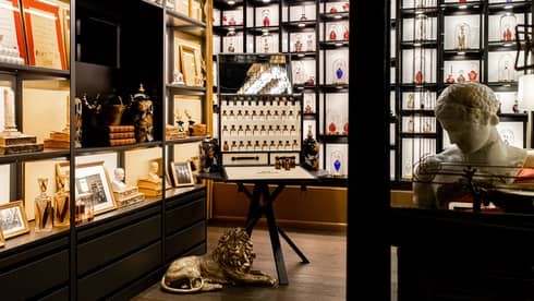 Store with various perfumes on display and a small marble sculpture.