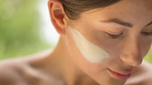 Close-up of side of woman's face with lotion on cheek