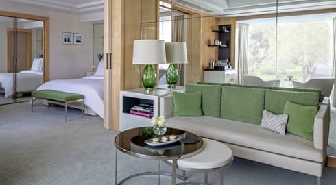 Mayfair Suite grey sofa with green pillows, round tables, alcove with bed, mirror