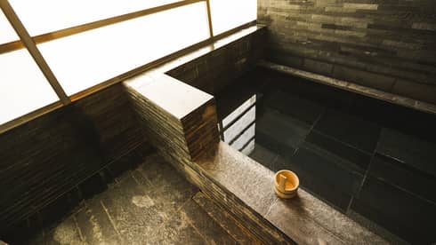 Rectangular black granite spa tub, small wood bowl on ledge