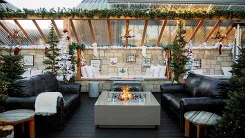 Outdoor terrace with two couches and a fire pit, and festive decorations.