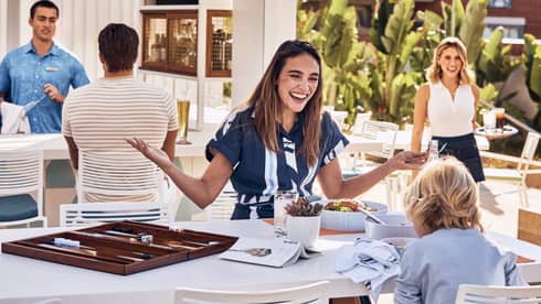 Woman and child laughing at table while sharing a meal.
