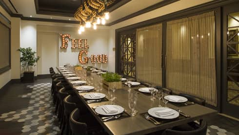 Long dining table in a private dining room with a large sign on the wall that says "Feel Good" in lightbulbs