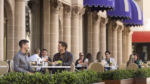 Small groups of people sitting and dining on an outside patio.