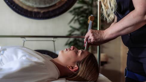 A woman receiving sound healing treatments at a spa.