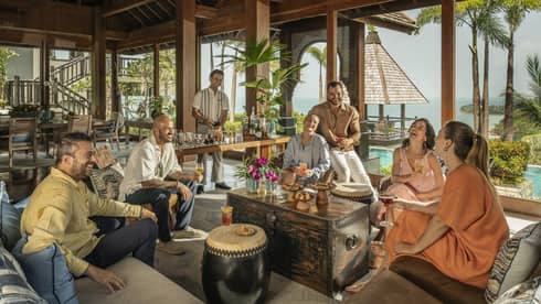 Laughing group of friends enjoy drinks made by their private bartender