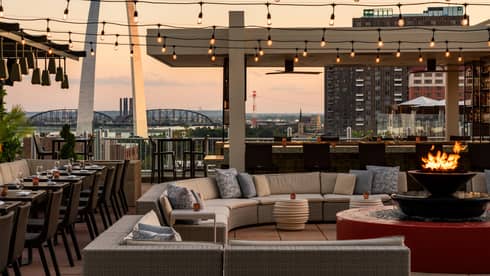Outdoor terrace with a couch, fire pit, and lights above.