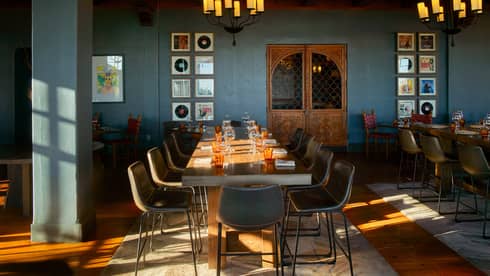 Dining room with blue walls and two chandeliers with candle lights.
