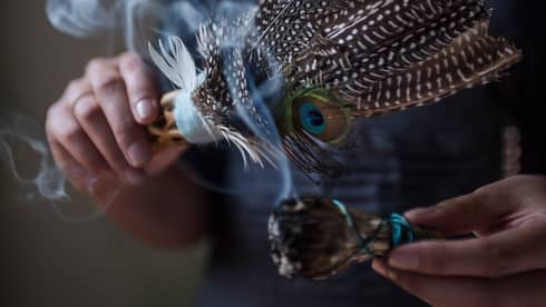 Close-up of smoke rising from sage, feathers used for smudging ceremony