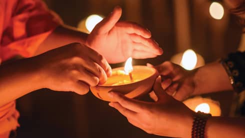 Buddhist monk hands holding candle cup in dark