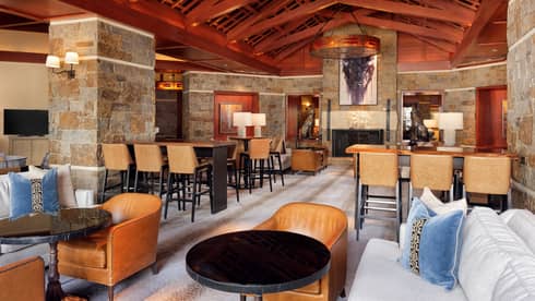 A lounge area with wood details, sofas, wood tables and chairs.
