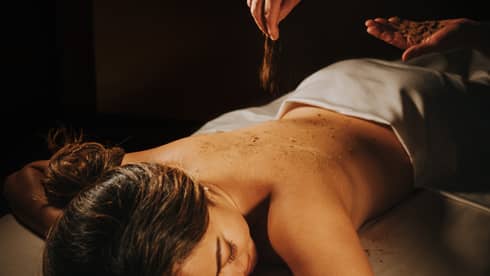 A guest in the 'Iliahi body cocoon, being moisturized with coconut oil and sprinkled with sandalwood powder