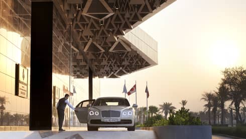 Four Seasons Hotel Kuwait doorman opens luxury car door near entrance 