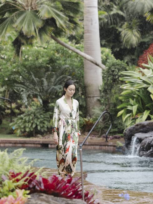 Woman in silk floral bathrobe walks near resort pool