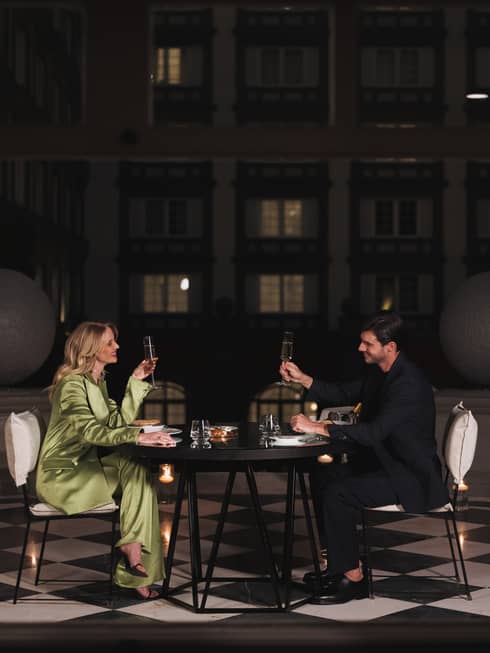 A man and woman drinking in a dimly lit room at a dark table.