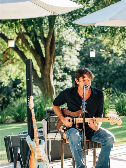 A man playing a guitar and singing outside.