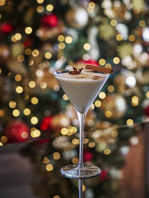 A cocktail in front of a Christmas tree.