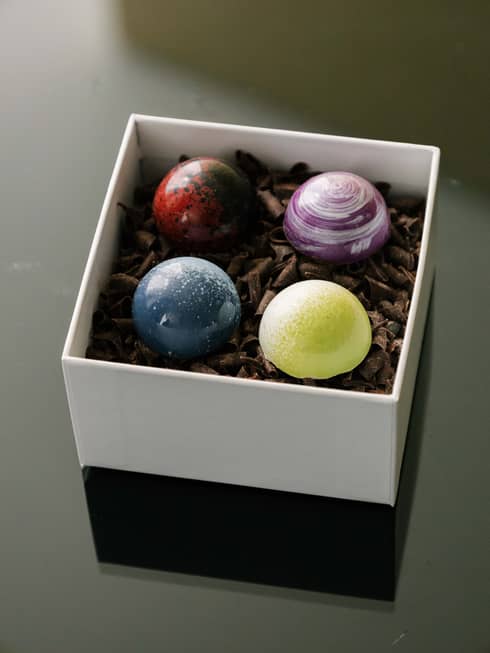 Box of chocolates with blue, yellow, purple and red coloured chocolates.