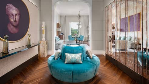 Room with turquoise, circular sofa, mirrored wall of closets, artwork
