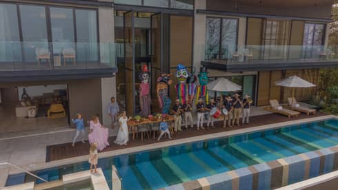 A family hosts an outdoor party on their pool patio complete with a live band and four Mojigangas, or traditional Mexican giant puppets