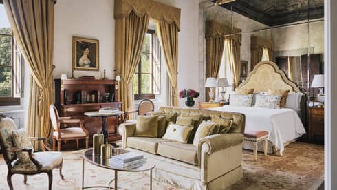 Renaissance Suite bedroom with a king bed, sitting area, elegant curtains and mirrored wall at Four Seasons Hotel Florence