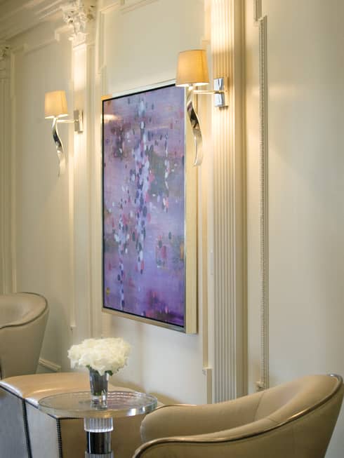 Oil painting on white wall by lamps, ivory armchairs, table with white flowers